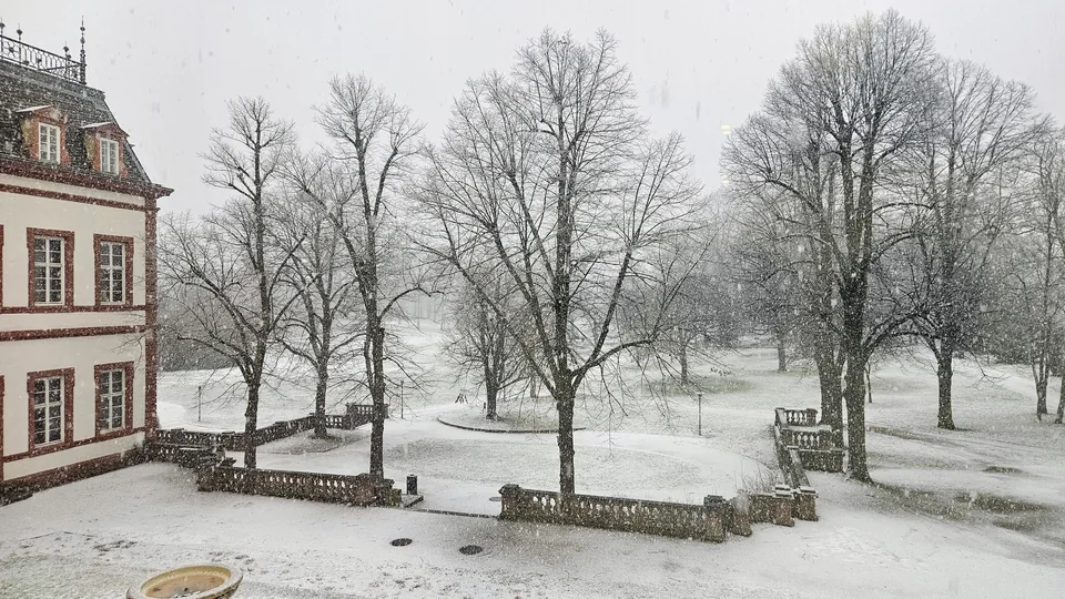 從二樓拱窗向外俯瞰漫天大雪中的巴洛克幾何庭園